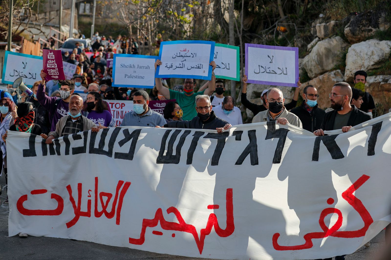 متظاهرون فلسطينيون يرفعون لافتات ضد عمليات الاستيطان الإسرائيلي في حي الشيخ جراح في القدس - AFP