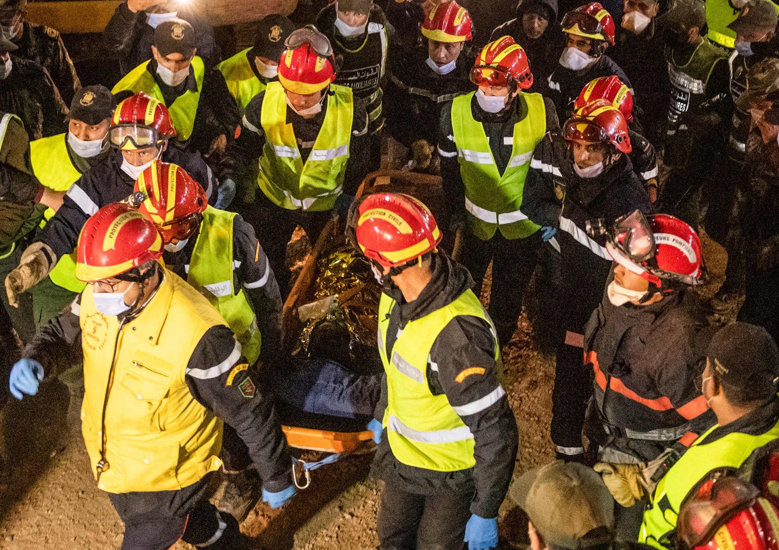 Moroccan emergency teams carry the body of five-year-old Rayan Oram to an ambulance after pulling him from a well shaft he fell into on February 1, in the remote village of Ighrane in the rural northern province of Chefchaouen, late on February 5, 2022. - Moroccan rescue crews found the five-year-old boy dead at the bottom of a well late on February 5, in a tragic end to a painstaking five-day operation that has gripped the nation. (Photo by Fadel SENNA / AFP) - AFP
