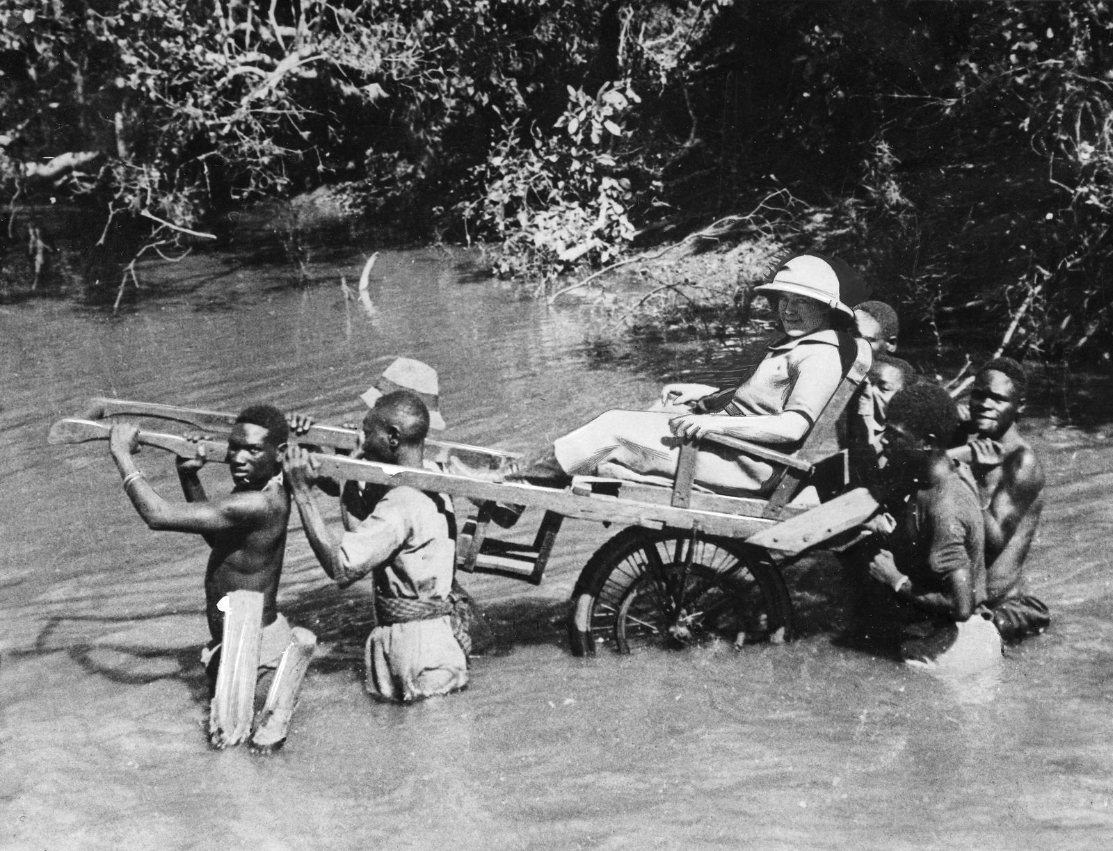 تظهر هذه الصورة المنشورة بتاريخ 1 يناير 1930 والتي التقطت في السنغال مسافراً أوروبياً يحمله حمالون أفارقة على كرسي عبر نهر - AFP