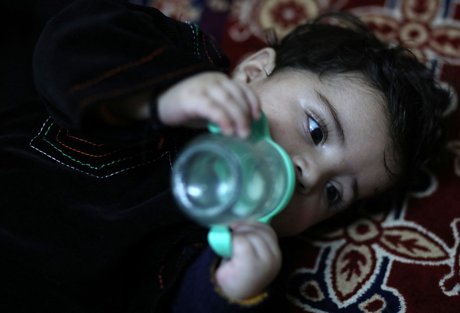 الطفل سهيل أحمدي يشرب حليباً من قارورة خلال وجوده في منزل صافي في كابل 7 يناير 2022 - REUTERS