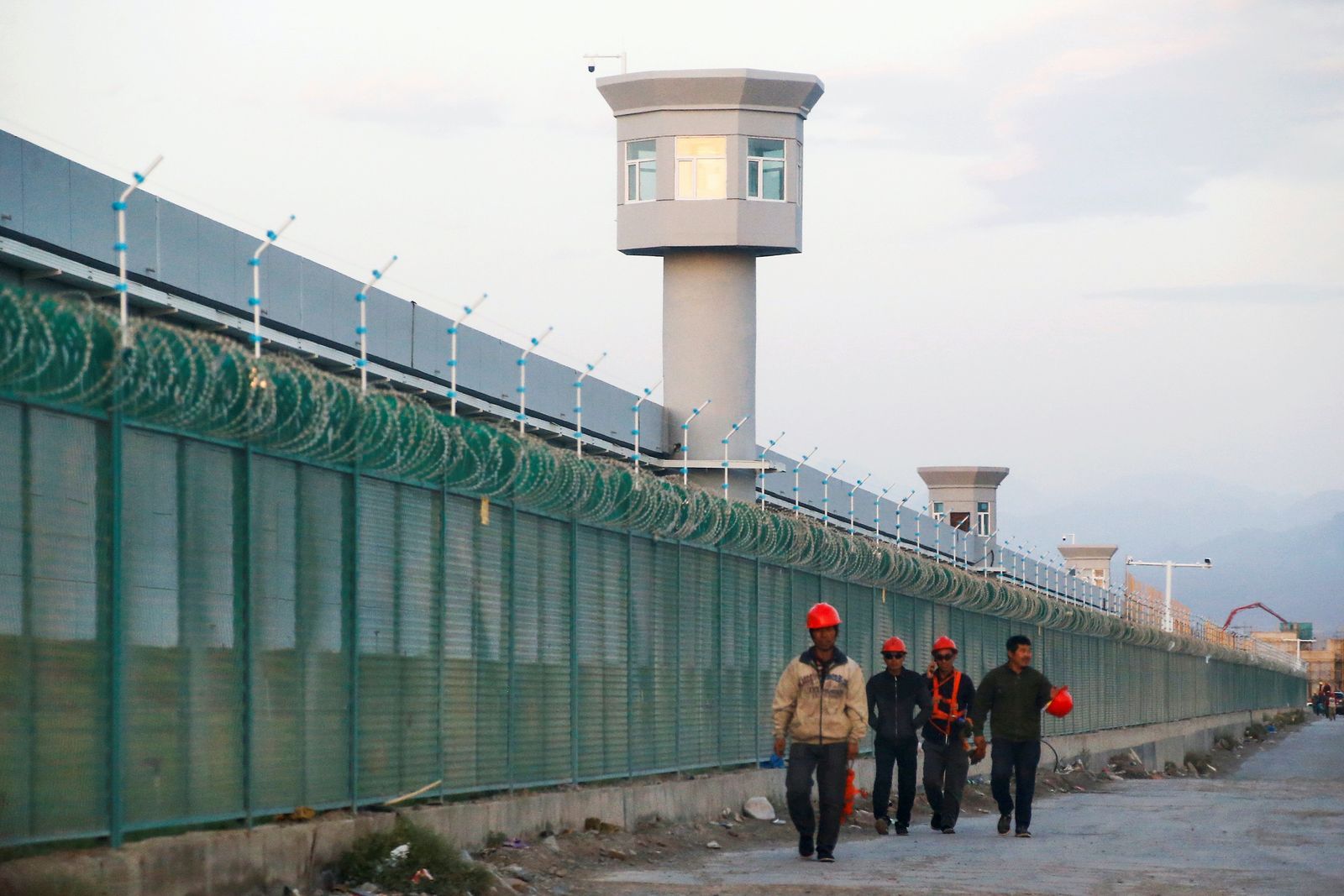عمال يسيرون بالقرب من السياج المحيط لما يعرف رسمياً باسم مركز تعليم المهارات المهنية في دابانتشنغ  03/12/2020. - REUTERS