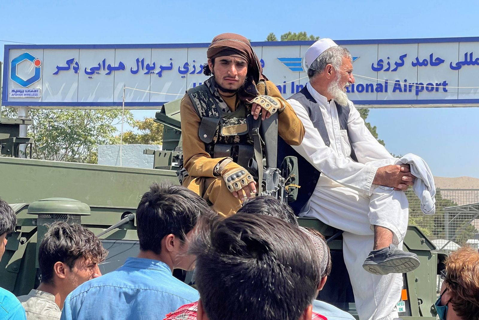 عنصر من طالبان (يسار) يجلس على عربة مصفحة خارج مطار كابول - 16 أغسطس 2021 - REUTERS