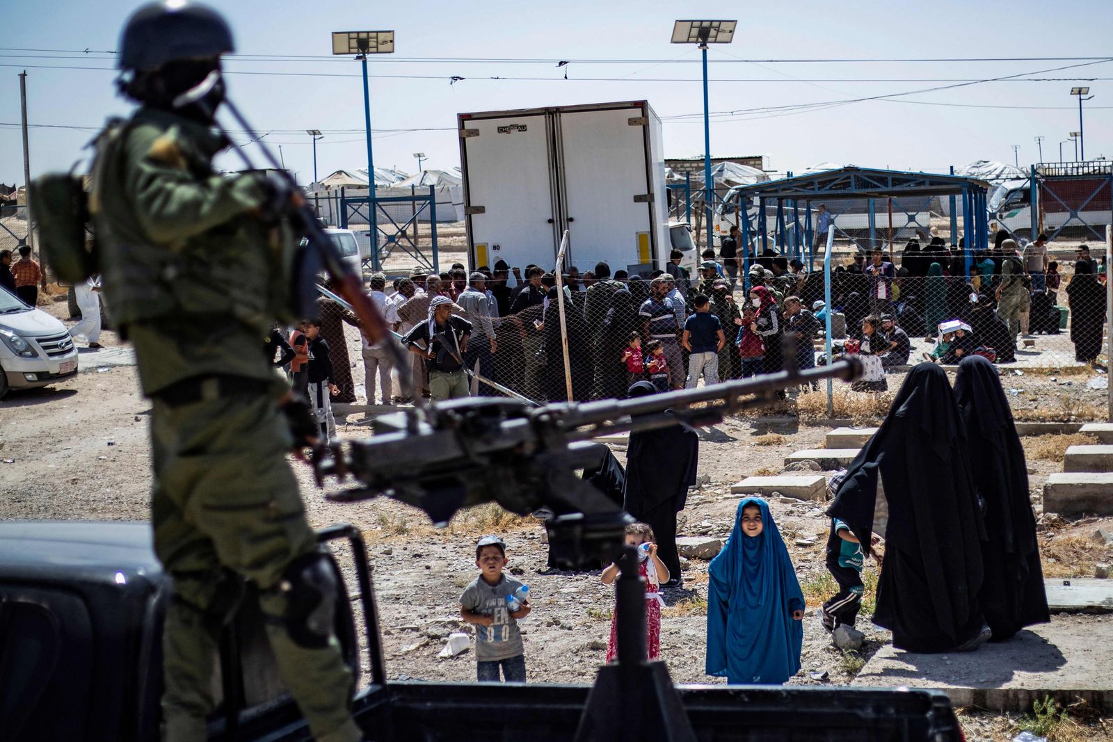 A member of Kurdish security forces stands guard as released detainees prepare to leave the Kurdish-run al-Hol camp, which holds relatives of suspected Islamic State (IS) group fighters in Syria's northeastern Hasakeh governorate on September 3, 2023, and return to their homes in Raqa. (Photo by Delil SOULEIMAN / AFP)