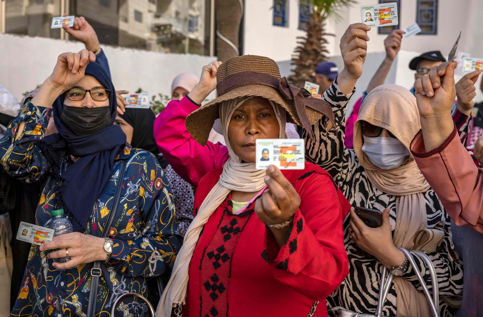 Moroccan workers gather with their work permits during a demonstration demanding the right to access the Spanish enclave of Ceuta without a visa, at Morocco's Fnideq border post on May 31, 2022. - Morocco and Spain have reopened the land borders between the north African country and the Spanish enclaves of Ceuta and Melilla, two years after they were shut due to Covid restrictions and a major diplomatic row. The reopening of the borders of the two enclaves initially remains limited to residents of Europe's open-borders Schengen area and their family members. (Photo by FADEL SENNA / AFP) - AFP