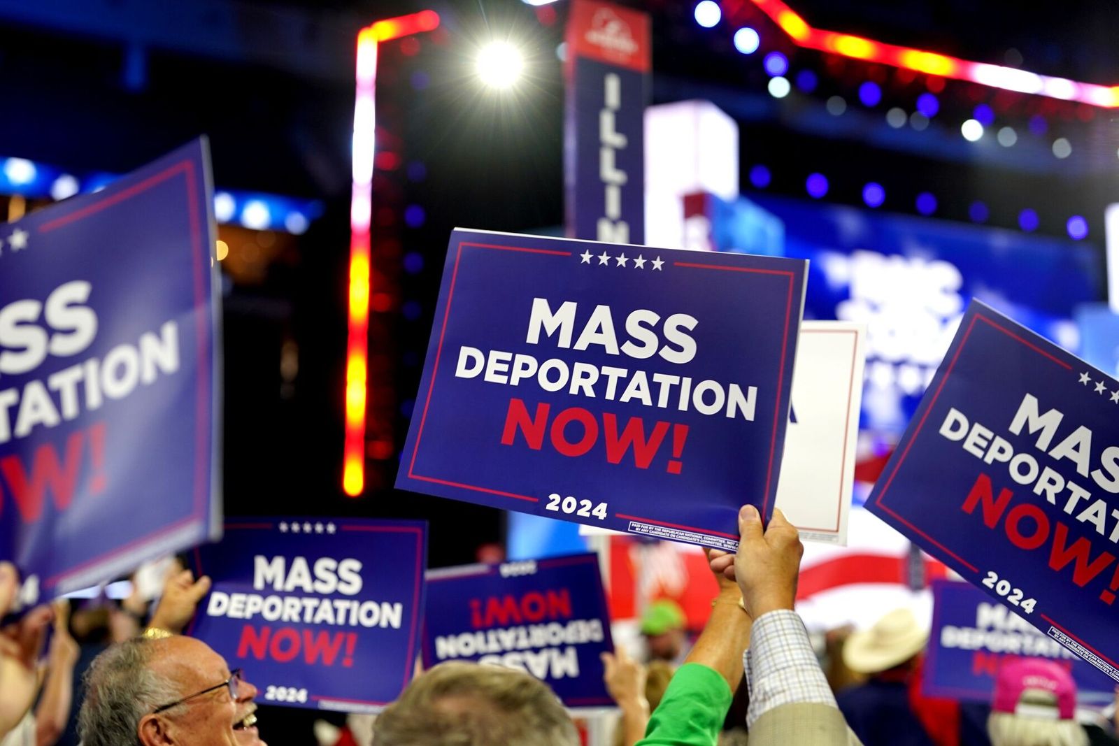 Delegates hold 'Mass Deportations Now' campaign signs during the Republican National Convention (RNC) at the Fiserv Forum in Milwaukee, Wisconsin, US, on Wednesday, July 17, 2024. The RNC chairman warned against complacency when his party concludes its official nominating jamboree this week with polls predicting ex-President Donald Trump prevailing over President Joe Biden in the November election. Photographer: Al Drago/Bloomberg Photographer: Al Drago/Bloomberg