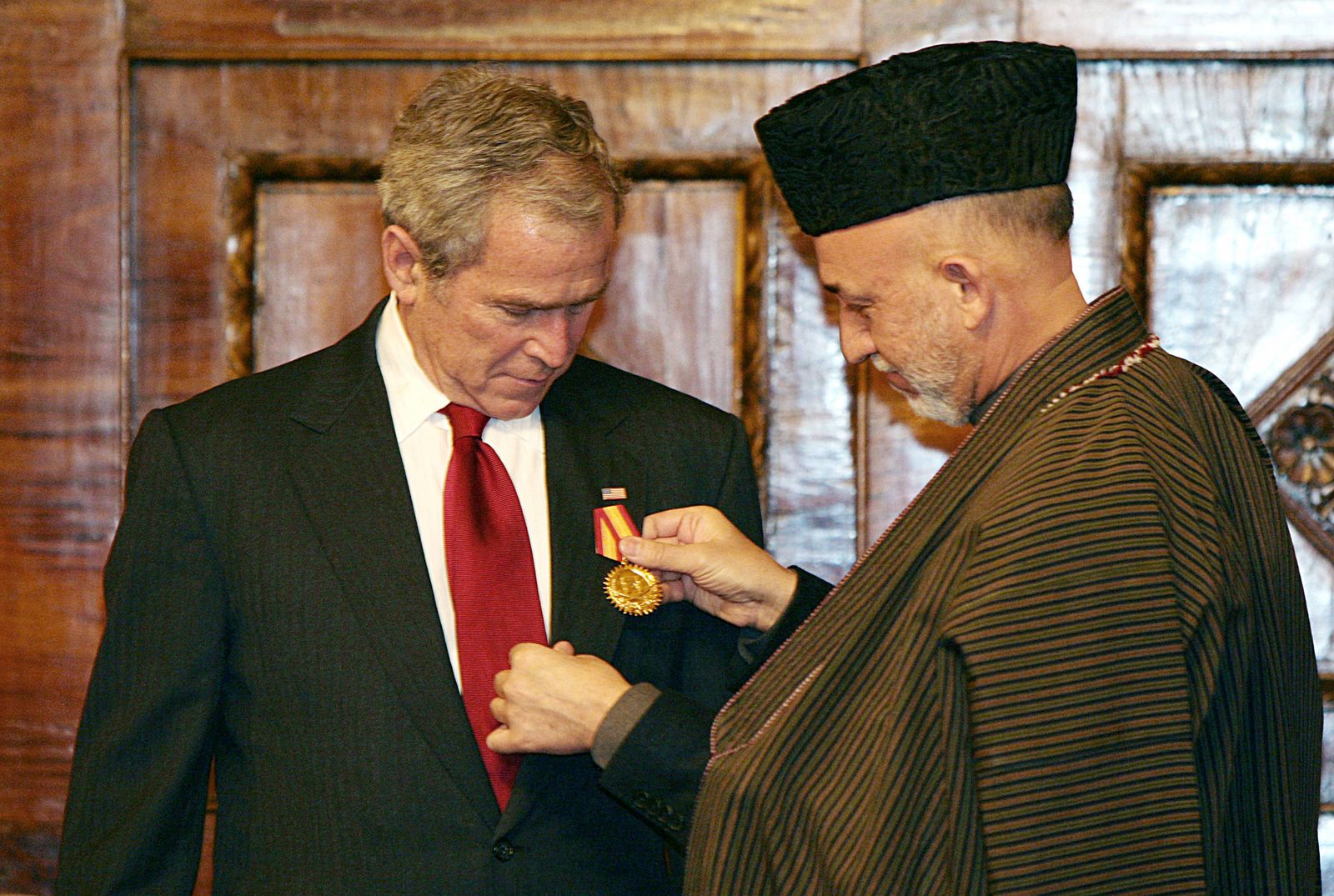 (FILES) In this file photo former Afghan President Hamid Karzai (R) presents US President George W. Bush with a medal at the Presidential Palace in Kabul on December 15, 2008. - Former US president George W. Bush said he has been watching the Taliban's lightning takeover of Kabul 