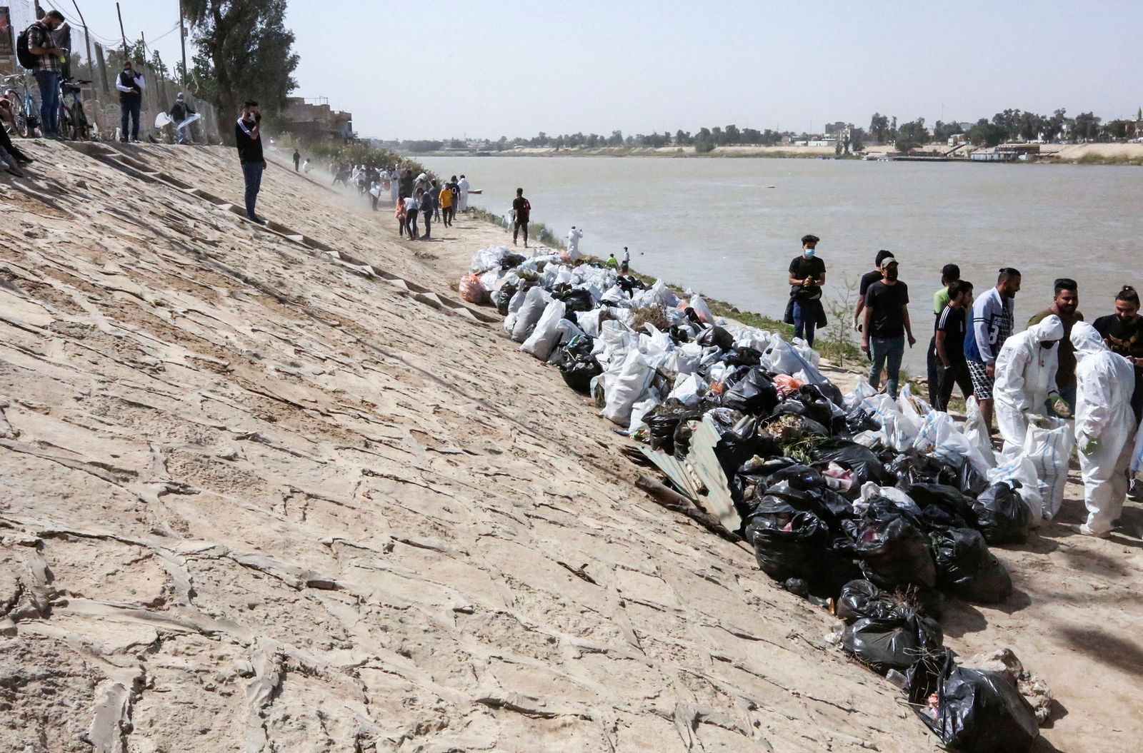 Young Iraqi volunteers take part in a clean-up campaign on the bank of the Tigris river in the Adhamiyah district of the capital Baghdad, on March 11, 2022. - Plastic garbage clogs the banks of Iraq's Tigris River in Baghdad, but an army of young volunteers is cleaning it, a rare environmental project in the war-battered country, part of a green activist campaign called the Cleanup Ambassadors. (Photo by Sabah ARAR / AFP) - AFP