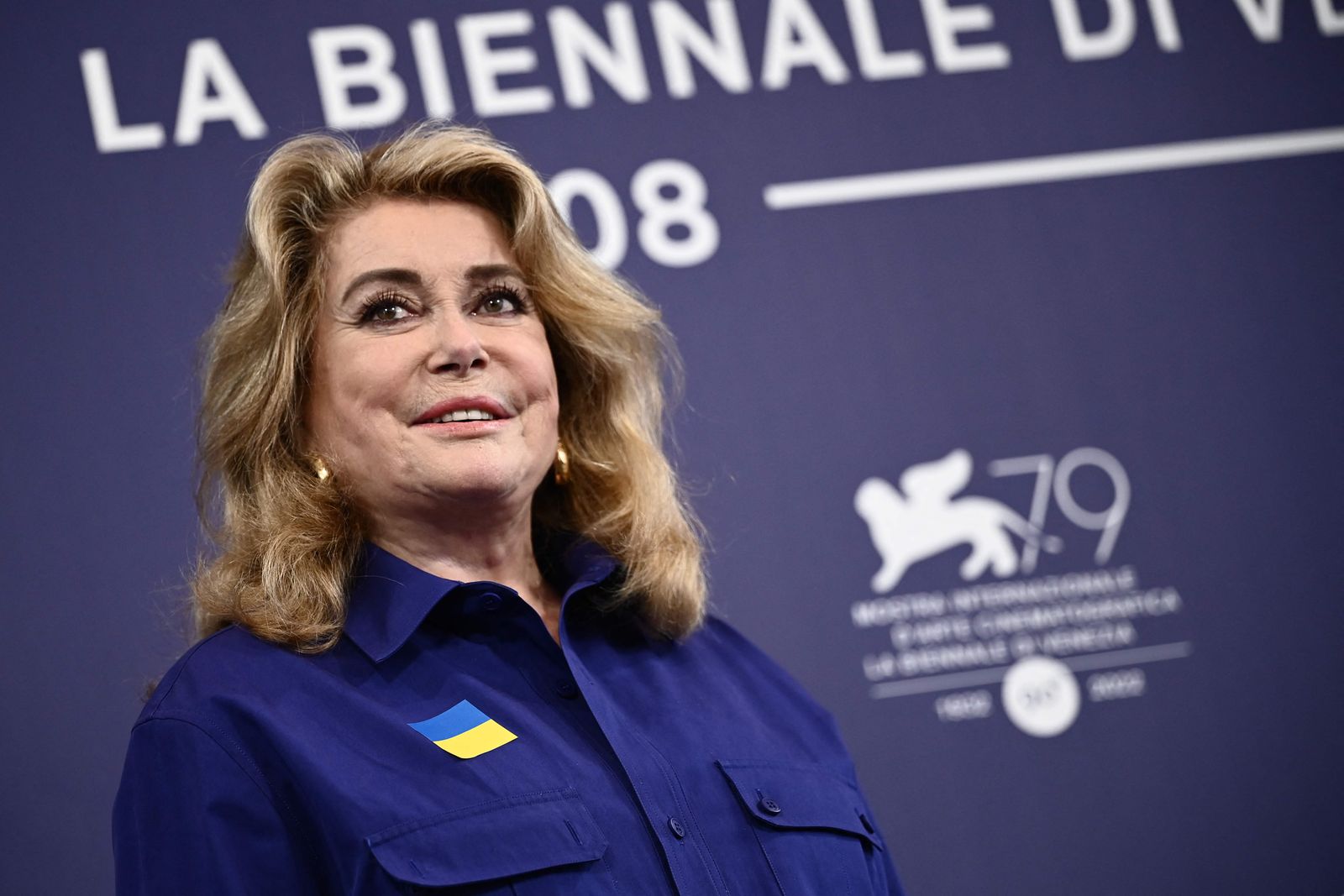 French actress Catherine Deneuve, wearing a flag of Ukraine on her shirt, poses on August 31, 2022, during a photocall for the Golden Lion for Lifetime Achievement she is to be awarded, on the opening day of the 79th Venice International Film Festival at Venice Lido. (Photo by Marco BERTORELLO / AFP) - AFP