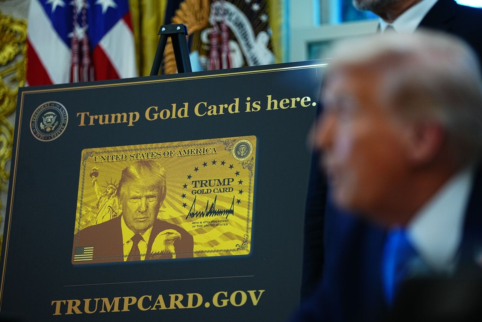 A Trump Gold Card sign as US President Donald Trump speaks to members of the media in the Oval Office of the White House in Washington, DC, US, on Friday, Sept. 19, 2025. Trump is signing a proclamation that would move to extensively overhaul the H-1B visa program, requiring a $100,000 fee for applications in a bid to curb overuse, according to a White House official familiar with the matter. Photographer: Aaron Schwartz/CNP/Bloomberg