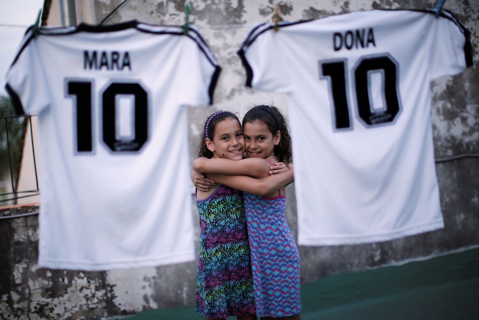 التوأمتان مارا ودونا يحتضنان بعضهما إلى جانب قميصيهما بالرقم 10، الذي كان يرتديه مارادونا - REUTERS
