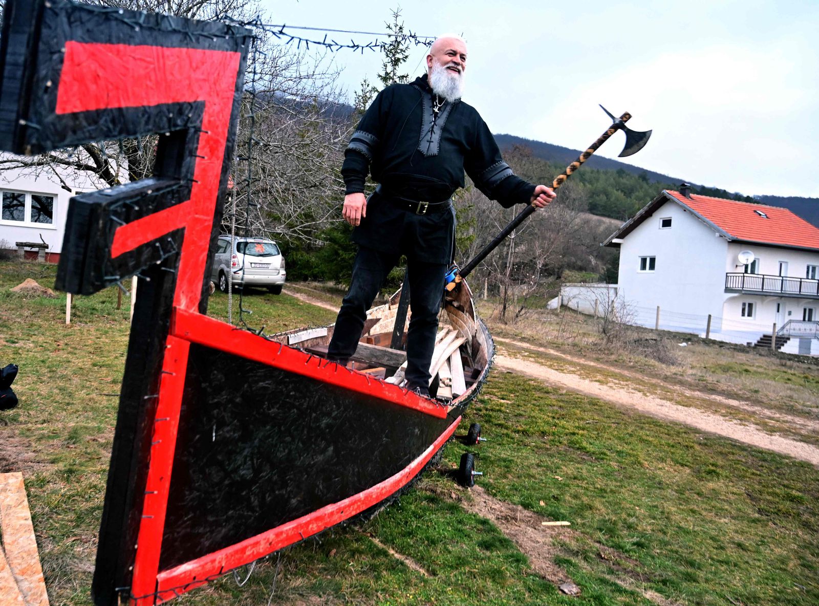 Stipe Pleic, also known by his Viking nickname of Ragnar Kavurson, holds an axe as he poses on a replica of a drakkar -- a flat-bottomed boat capable of crossing oceans -- which he built, in the western-Bosnian town of Tomislavgrad on January 5, 2022. - Some 6 years ago, Pleic developed fascination for Nordic culture and history. Since than he used his previous knowledge and experience in metal and wood work and started crafting traditional Viking axes and knives. He retreated to his father's old stone house where he established his workshop and somewhat of a Viking armaments museum. According to Pleic, in his workshop, he finds a little peace and escape from harsh reality of life in Bosnia and Herzegovina. (Photo by ELVIS BARUKCIC / AFP) - AFP