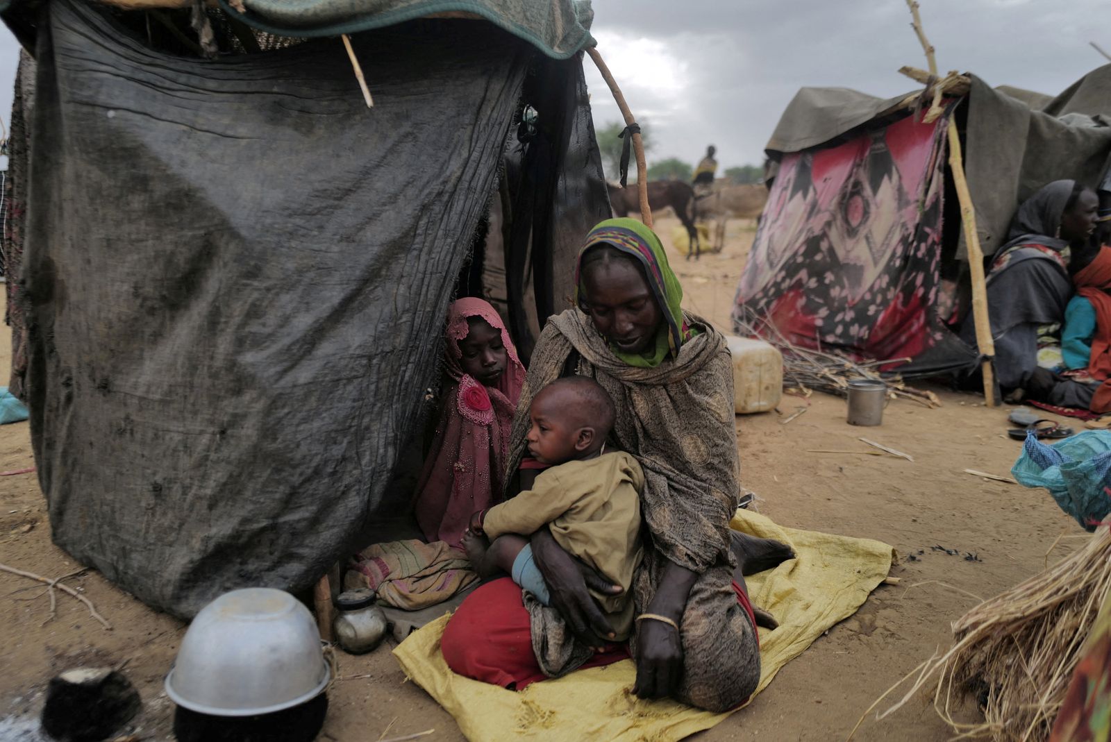 سودانية فرت من العنف في إقليم دارفور بالسودان تجلس مع أطفالها بجوار مأواهم المؤقت في تشاد قرب الحدود السودانية. 11 مايو 2023 - REUTERS