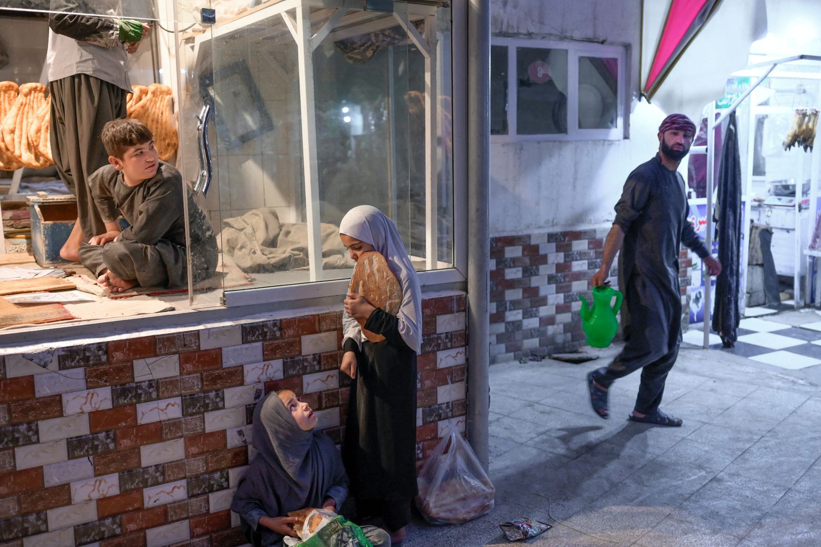 فتاتان أفغانيتان تنتظران خبزاً مجانياً أمام فرن في كابول، 14 سبتمبر 2021 - AFP