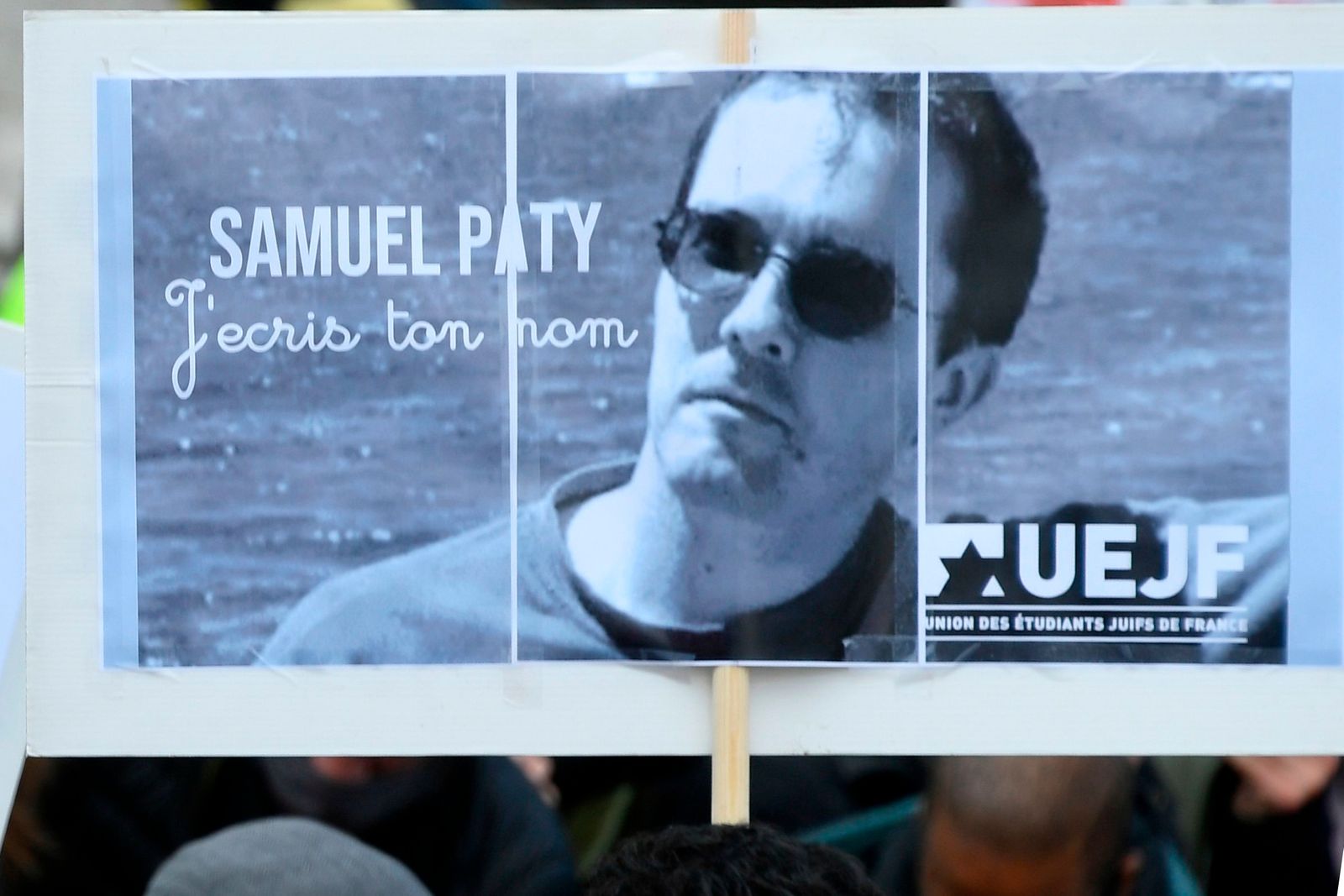 A person holds a placard with the portrait of history teacher Samuel Paty as people gather on Place de la Republique in Paris on October 18, 2020, two days after he was beheaded by an attacker who was shot dead by policemen. - Thousands of people rally in Paris and other French cities on October 18 in a show of solidarity and defiance after a teacher was beheaded for showing pupils cartoons of the Prophet Mohammed. His murder in a Paris suburb on October 16 shocked the country and brought back memories of a wave of Islamist violence in 2015. (Photo by Bertrand GUAY / AFP) - AFP