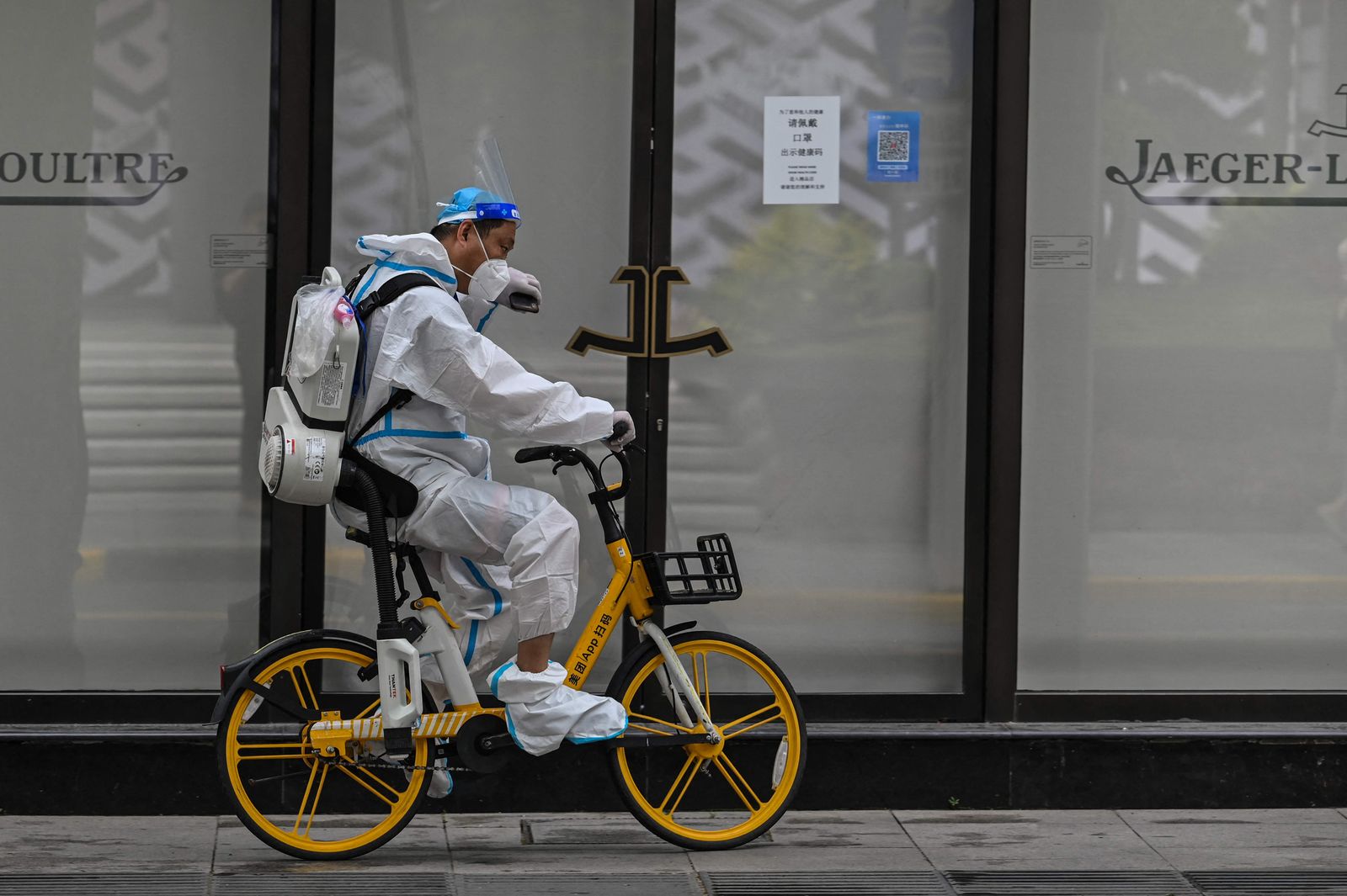 A worker rides a bicycle on a street in the Jing'an district of Shanghai on June 1, 2022, after the end of the lockdown that kept the city two months with heavy-handed restrictions. (Photo by Hector RETAMAL / AFP) - AFP
