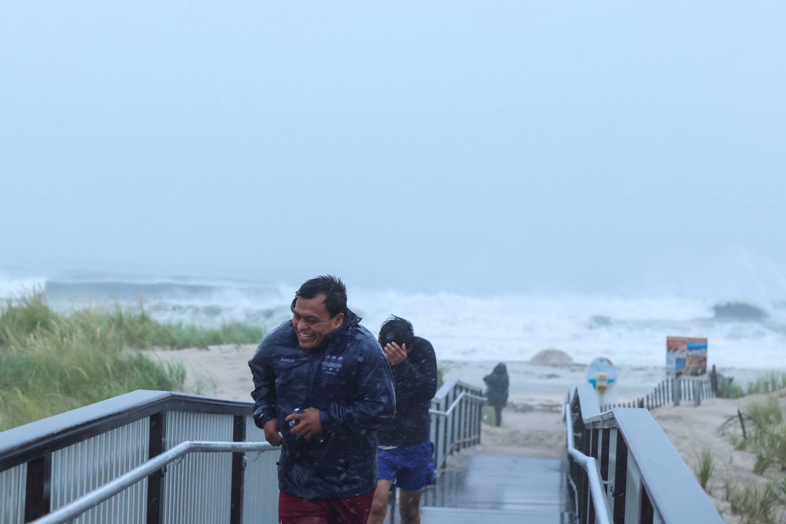  أشخاص عائدين من مشاهدة الأمواج على شاطئ بونكوج بينما انخفض الإعصار هنري إلى عاصفة استوائية. - REUTERS