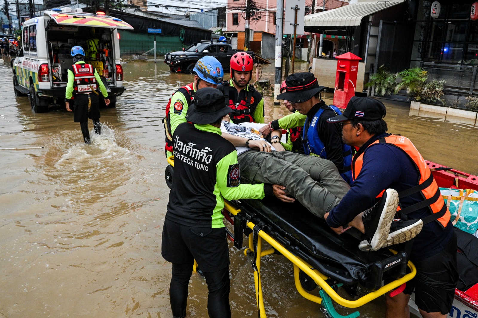 رجال إنقاذ يحملون شخصاً على نقالة أثناء نقلهم إلى المستشفى في شارع غمرته المياه في منطقة هات ياي المتضررة من الأمطار الغزيرة التي أثرت على عدة مقاطعات في جنوب تايلندا. 26 نوفمبر 2025