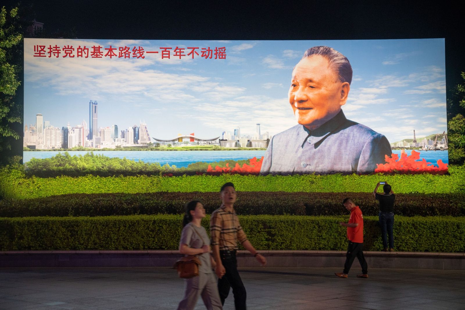 يسيرون أمام صورة للزعيم الصيني الراحل دينغ شياو بينغ في شينزن - 19 نوفمبر 2020 - Bloomberg