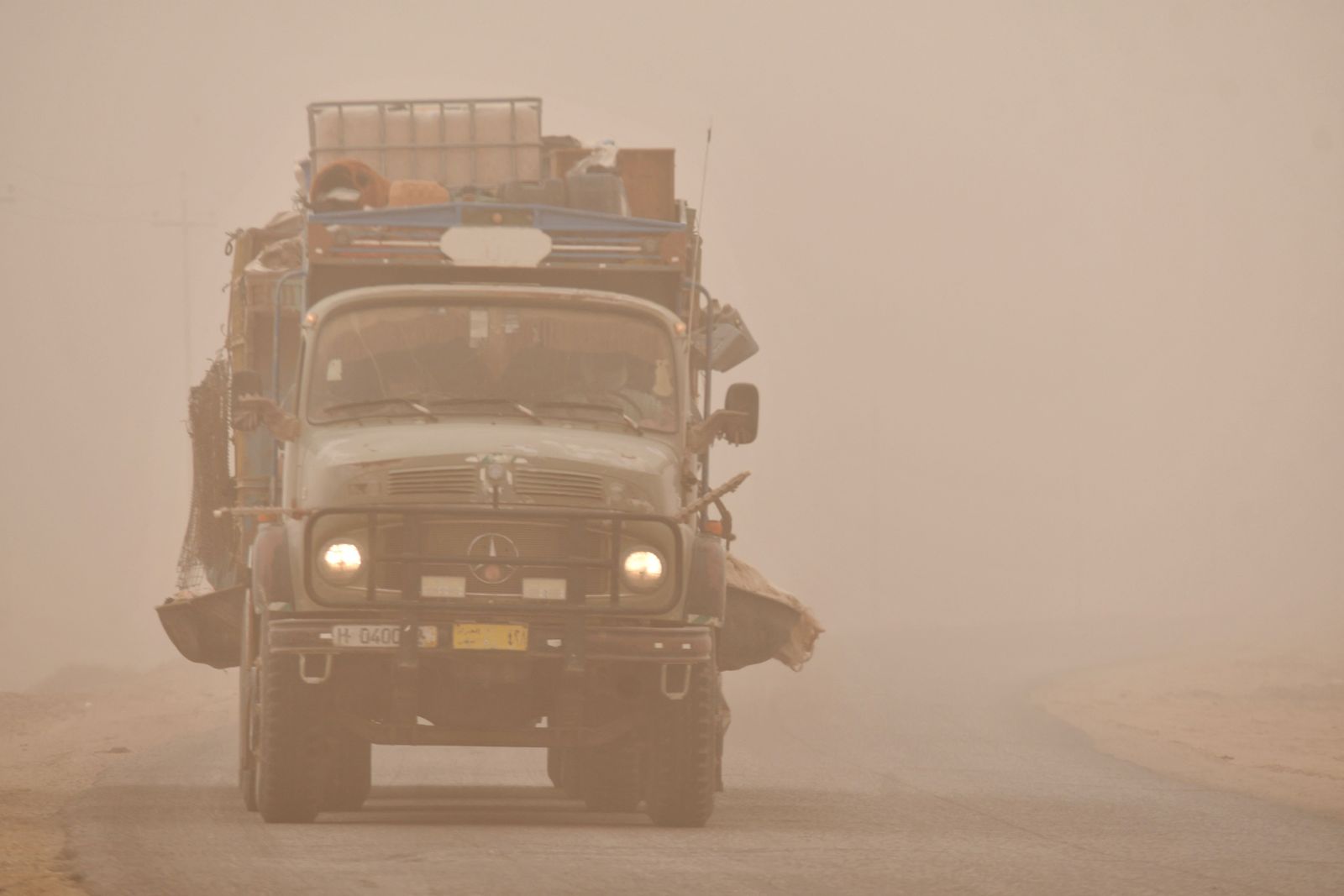 A picture taken on May 5, 2022 shows a truck driving through a Spring sandstorm in the southern Iraqi city of Nasiriyah in the Dhi Qar province. - Iraq is yet again covered in a thick sheet of orange as it suffers the latest in a series of dust storms that have become increasingly common. The country was hammered by a series of such storms in April, grounding flights and leaving dozens hospitalised with respiratory problems. (Photo by Asaad NIAZI / AFP) - AFP