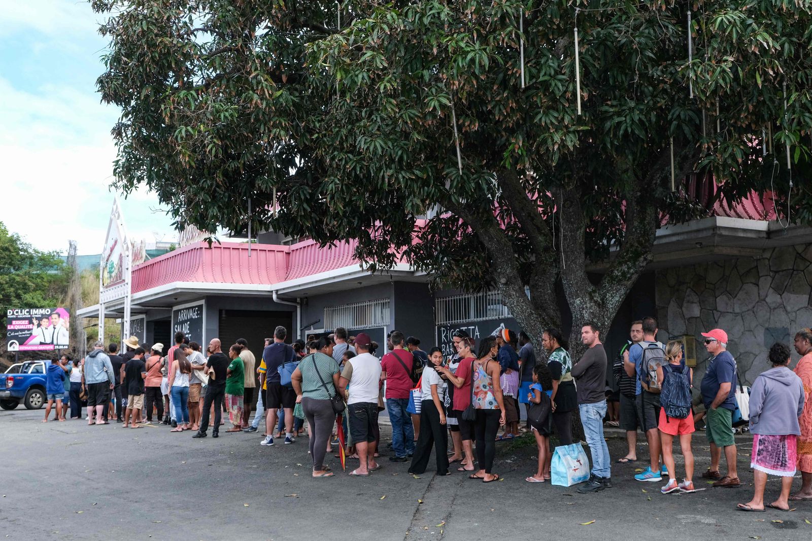 People wait in line to enter a general store that remained open in the Magenta district of Noumea on May 15, 2024 amid protests linked to a debate on a constitutional bill aimed at enlarging the electorate for upcoming elections of the overseas French territory of New Caledonia. More than 130 people have been arrested in New Caledonia as violent protests rock the French Pacific archipelago, the government said on May 15, 2024, as Paris adopted the constitutional reform that angered pro-independence forces. (Photo by Theo Rouby / AFP)