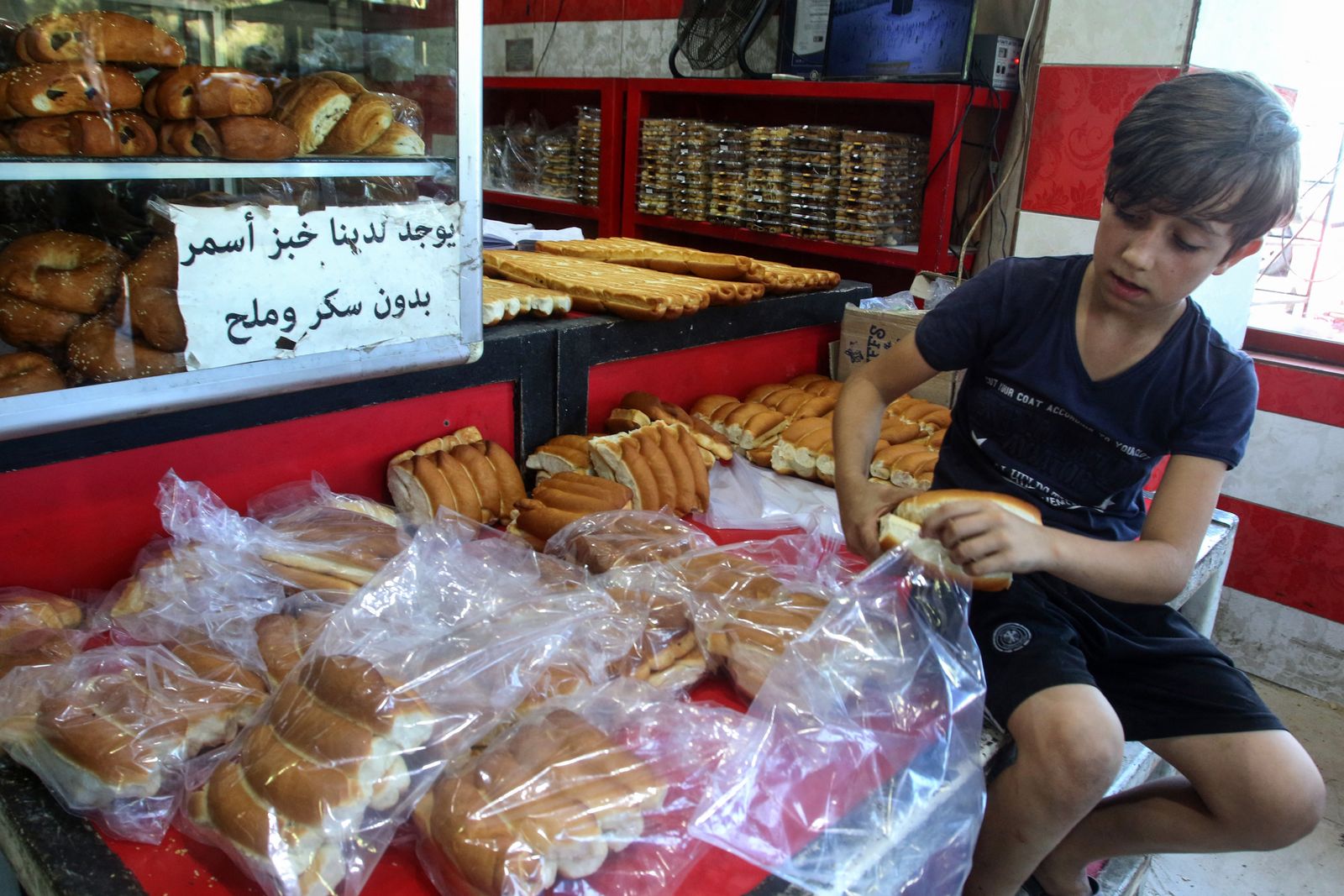 صبي لبناني يحمل خبزاً في فرن بمدينة صيدا مع اصطفاف الأهالي للحصول على الخبز 13 أغسطس 2021 - AFP