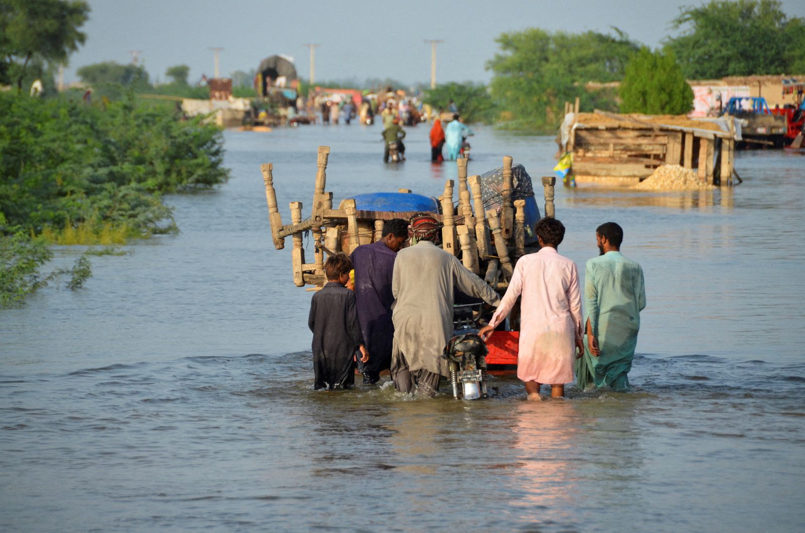رجال يسيرون على طول طريق غمرته المياه بعد هطول الأمطار والفيضانات في سوهباتبور، باكستان- 28 أغسطس 2022 - REUTERS