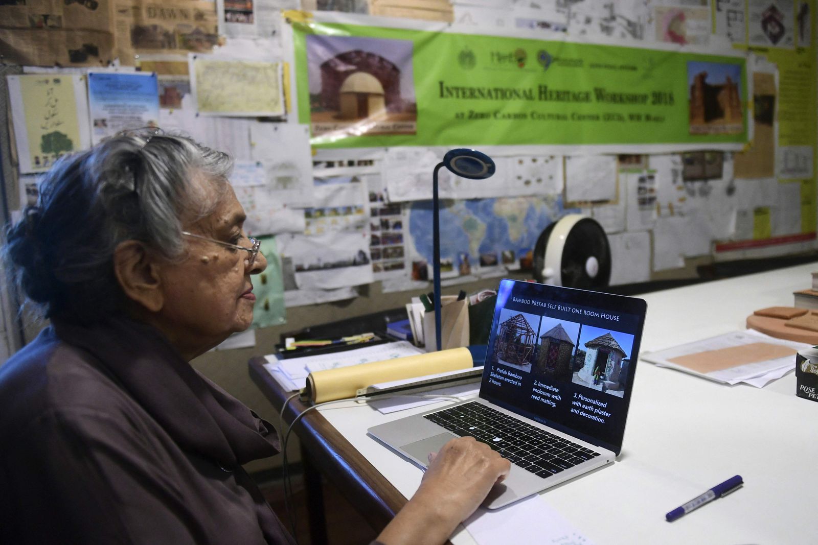 In this picture taken on April 10, 2023, architect Yasmeen Lari, the head of Heritage Foundation of Pakistan, shows pictures of huts on a laptop at her office in Karachi. At 82 years old, architect Yasmeen Lari is forging the way in fortifying Pakistan's rural communities, who are living on the frontline of climate change. (Photo by Asif HASSAN / AFP) - AFP