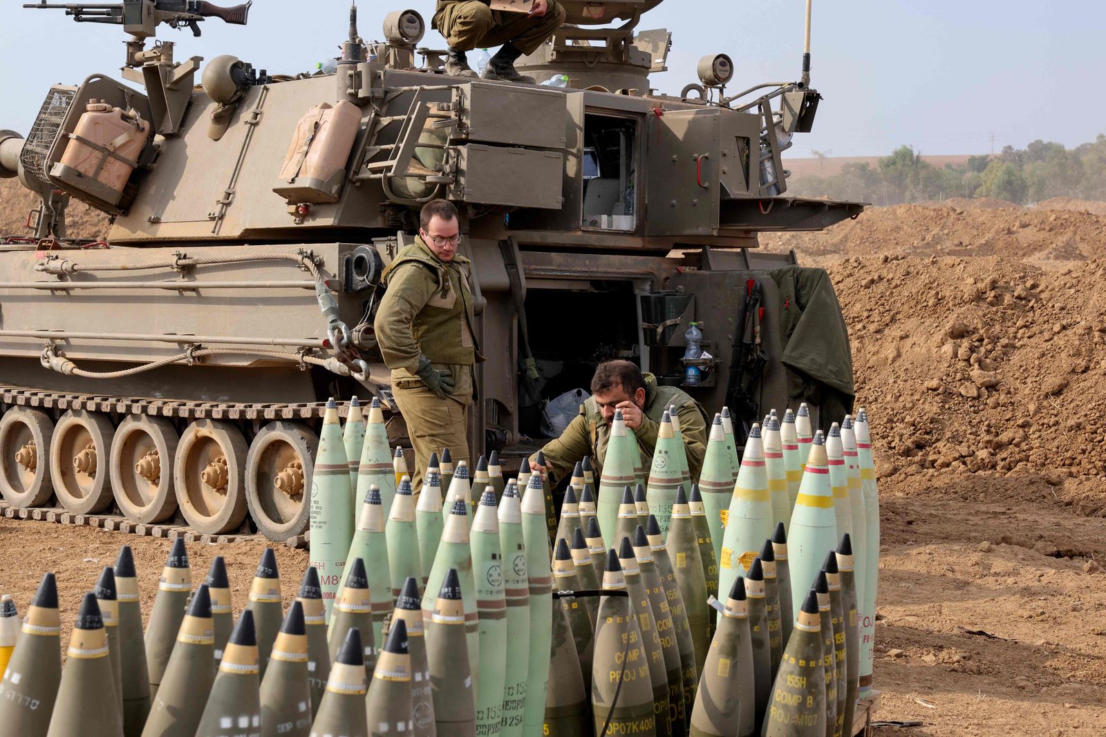 Artillery shells are lined up next to an armoured vehicle as Israeli soldiers take positions near the border with Gaza in southern Israel on October 9, 2023. Stunned by the unprecedented assault on its territory, a grieving Israel has counted over 700 dead and launched a withering barrage of strikes on Gaza that have raised the death toll there to 493 according to Palestinian officials. (Photo by JACK GUEZ / AFP)