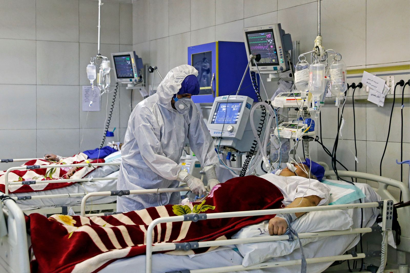 مسعف إيراني يعالج مريضاً مصاباً بفيروس كورونا في مستشفى بطهران - AFP