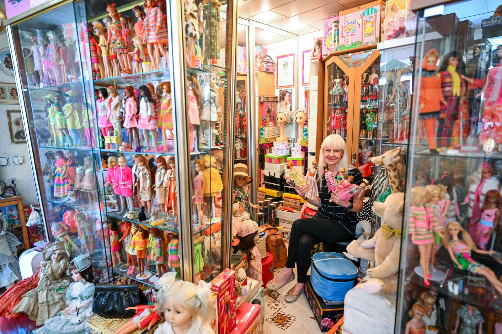 Barbie collector Bettina Dorfmann holds some of her rare Barbies as she sits among hundres of dolls at her 