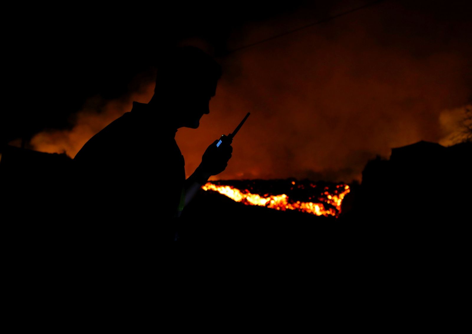 Lava flows next to a local police officer following the eruption of a volcano in Spain - REUTERS