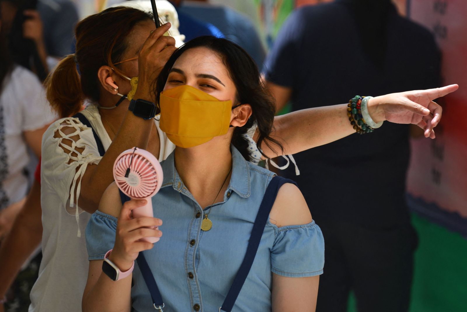 A woman uses a fan to keep cool during the presidential election at a polling station in Manila on May 9, 2022. (Photo by CHAIDEER MAHYUDDIN / AFP) - AFP