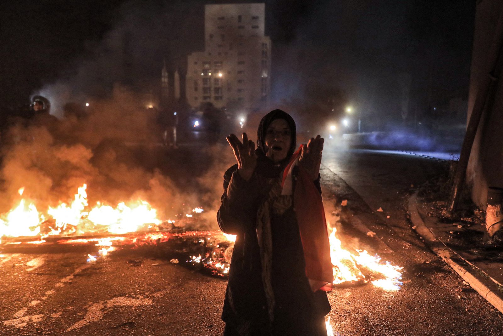 امرأة تتفاعل وتقف بالقرب من إطارات مشتعلة تقطع طريقًا في وسط العاصمة اللبنانية بيروت في 2 مارس 2021 خلال احتجاج على تدهور الأوضاع الاقتصادية والاجتماعية - AFP