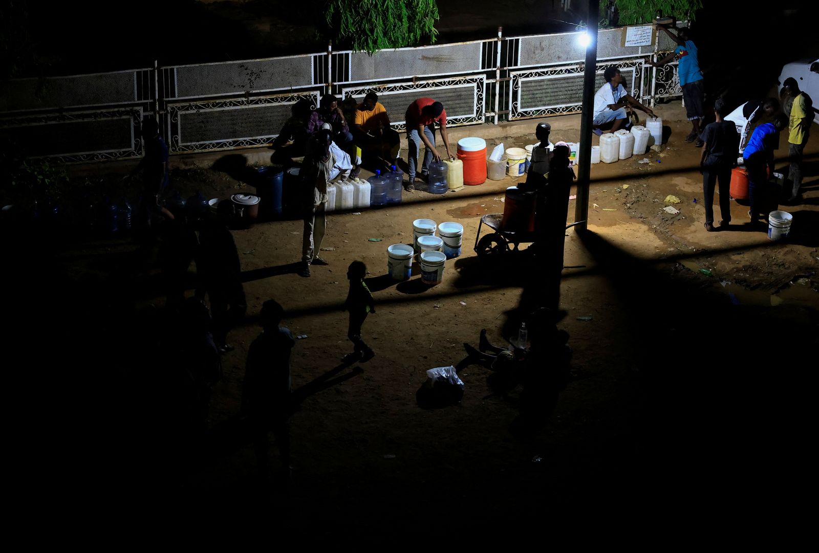 سودانيون يتجمعون للحصول على المياه باستخدام مولد كهربائي بسبب انقطاع التيار الكهربائي مع استمرار الاشتباكات بين قوات الدعم السريع والجيش السوداني، في الخرطوم بحري ، السودان- 12 مايو  2023.  - REUTERS