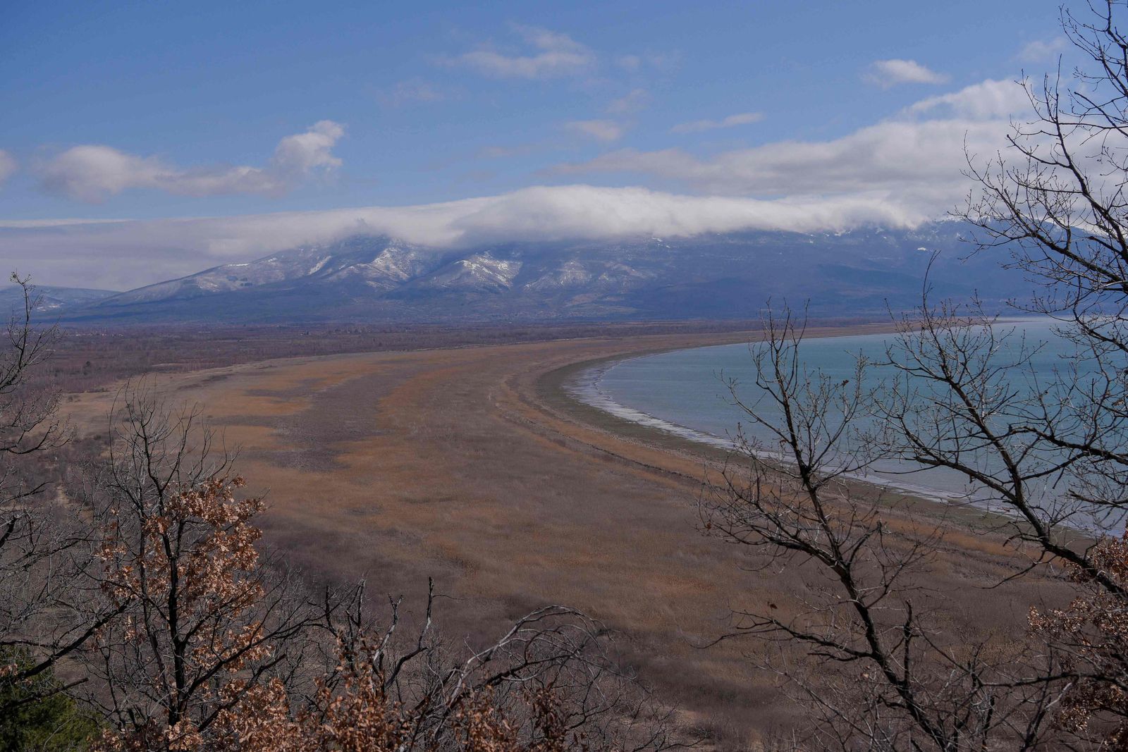 This photograph taken on March 17, 2023, shows a general view of the Prespa lake near Otesevo, in North Macedonia. - For millions of years Lake Prespa was pristine. But following decades of climate change, over consumption and pollution, the prehistoric body of water in southeast Europe is shrinking at an alarming rate. Straddling the borders of Albania, Greece and North Macedonia, Lake Prespa is believed to be home to thousands of species that rely on the water and its surrounding habitat.  But warming temperatures have wreaked havoc on the annual snowfall in the area, drying up vital streams that feed into Prespa, putting the species that depend on the lake and another nearby body of water at risk. (Photo by Armend NIMANI / AFP) - AFP