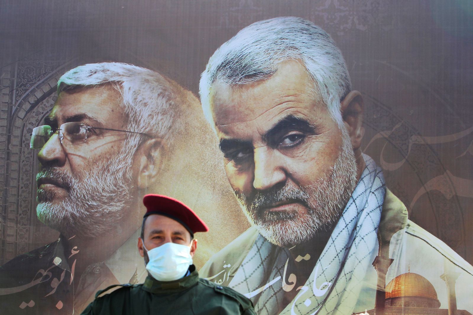 أحد عناصر حزب الله اللبناني أمام لوحة للقائد السابق لفيلق القدس بالحرس الثوري الإيراني قاسم سليماني  - REUTERS