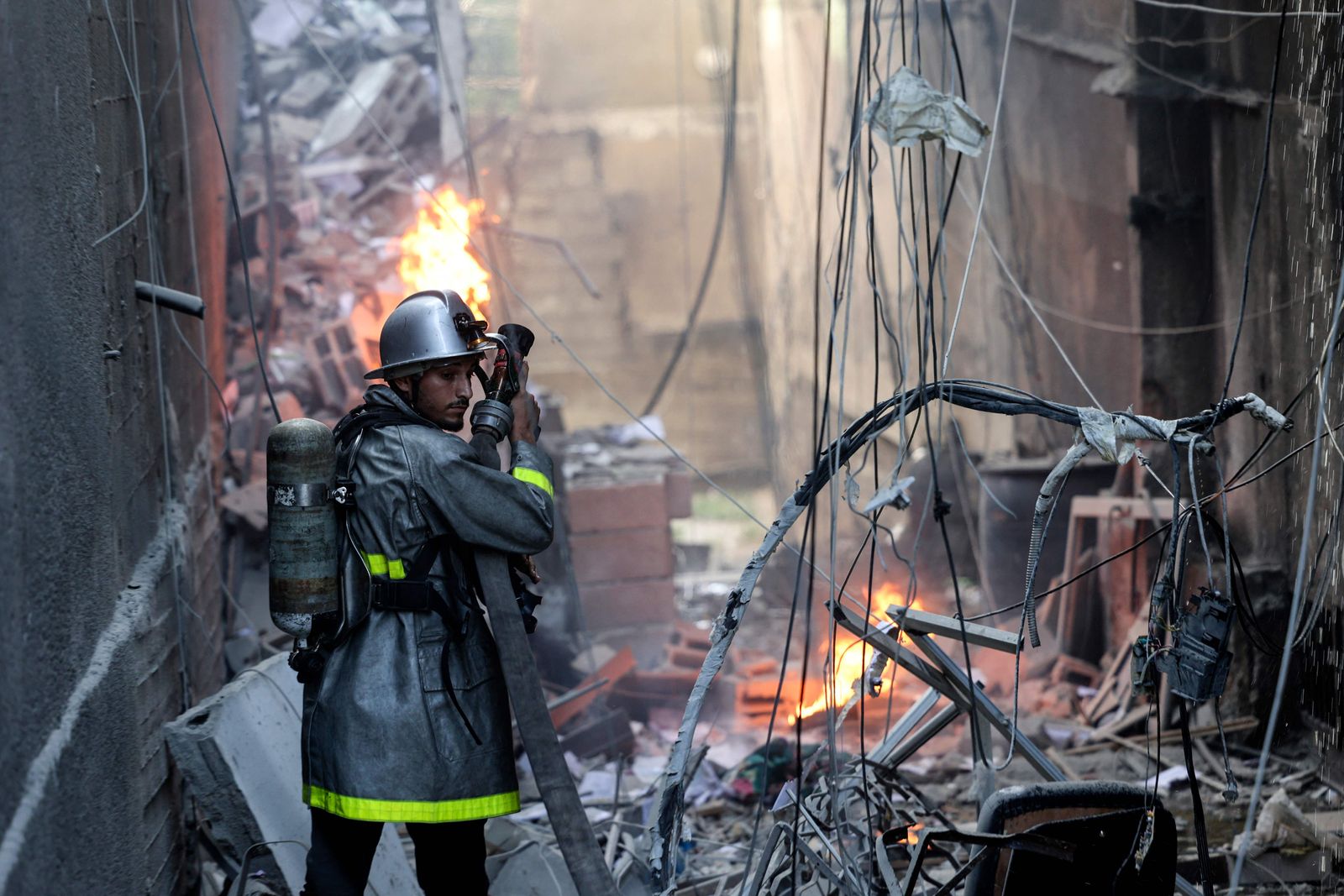 A Palestinian firefighter fights the blaze amid the destruction following an Israeli air strike on Gaza City, on August 5, 2022. - The Israeli military said today it launched air strikes on Gaza, which were witnessed by Palestinians in central Gaza City. (Photo by Mohammed ABED / AFP) - AFP