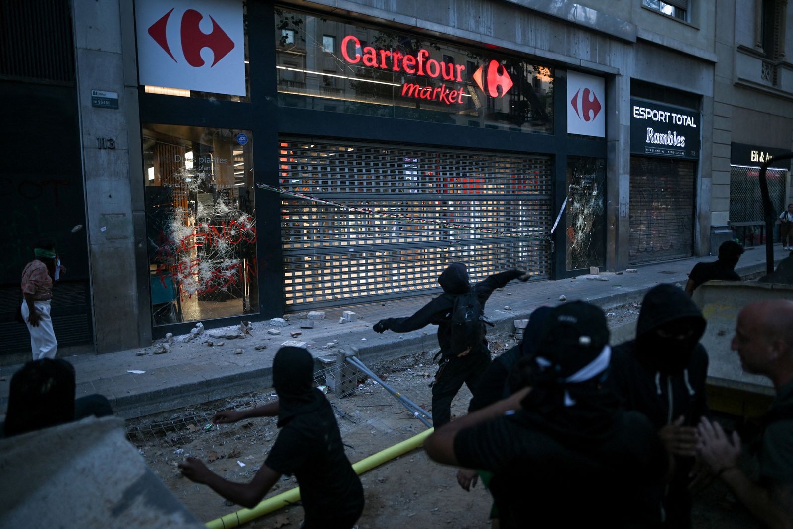 A demonstrator throws an object at a Carrefour shop, as people attend a pro-Palestinian protest condemning Israeli forces' interception of the Global Sumud Flotilla vessels which were aiming to reach Gaza and break Israel's naval blockade, in Barcelona, Spain, October 4, 2025. REUTERS/Lorena Sopena     TPX IMAGES OF THE DAY