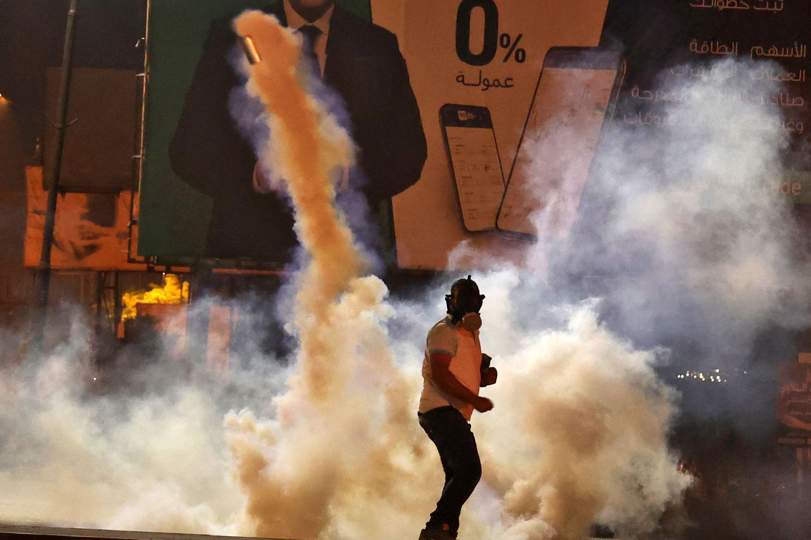 A Palestinian protester stands amid tear gas fired by Israeli security forces at the Hawara checkpoint, south of Nablus city, in the occupied West Bank on May 8, 2021. (Photo by JAAFAR ASHTIYEH / AFP) - AFP