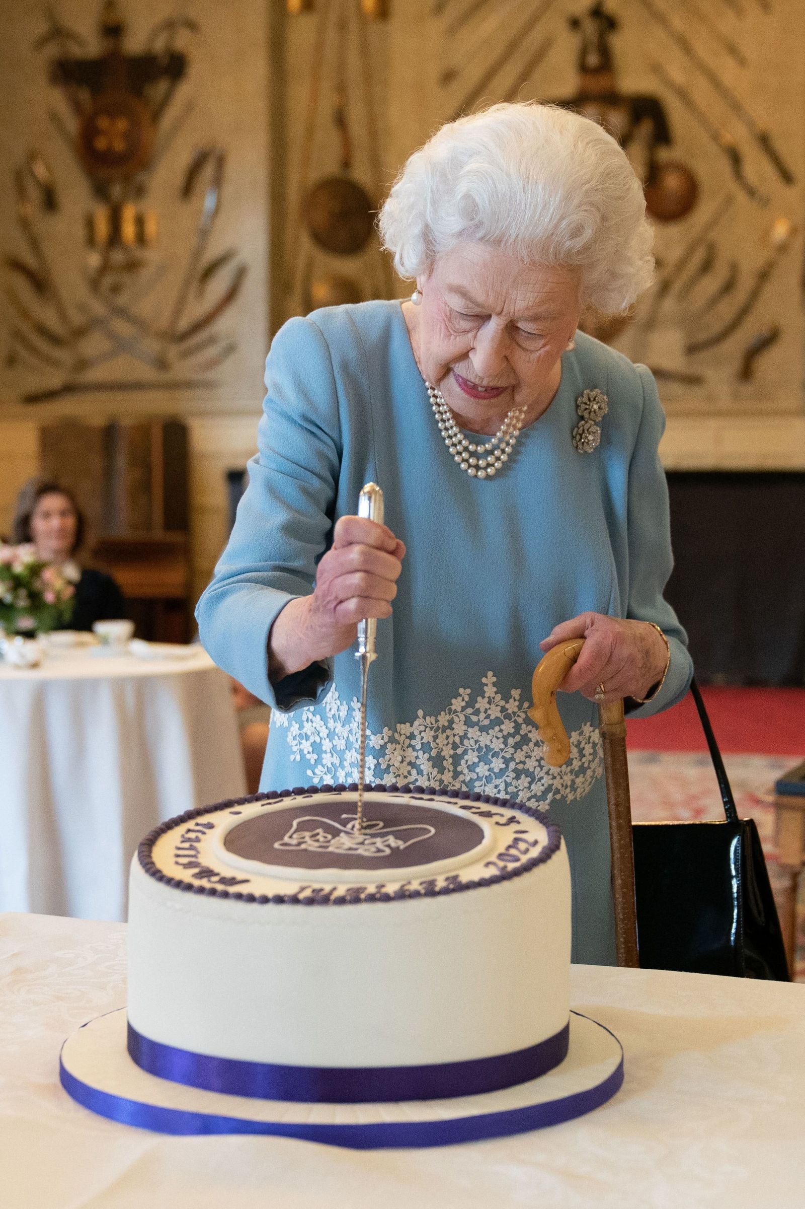 ملكة بريطانيا إليزابيث الثانية تقطع كعكة للاحتفال ببداية اليوبيل البلاتيني خلال حفل استقبال في مقر إقامة الملكة في نورفولك. 5 فبراير 2022  - AFP