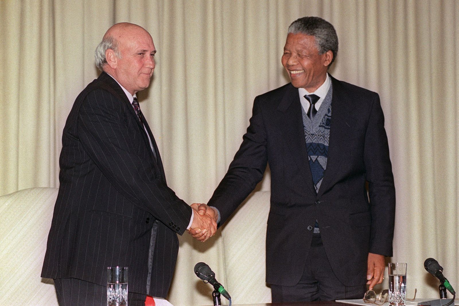 (FILES) In this file photo taken on August 07, 1990 South African president Frederik W. de Klerk (L) and anti-apartheid leader and African National Congress (ANC) member Nelson Mandela (R), smile and shake hands after at a joint press conference in Pretoria, following a marathon meeting between South African governement and ANC, in which ANC agreed to suspend its 29 years of armed struggle. - FW de Klerk, South Africa's last white president, has died aged 85, his foundation announced on November 11, 2021. (Photo by ALEXANDER JOE / AFP) - AFP