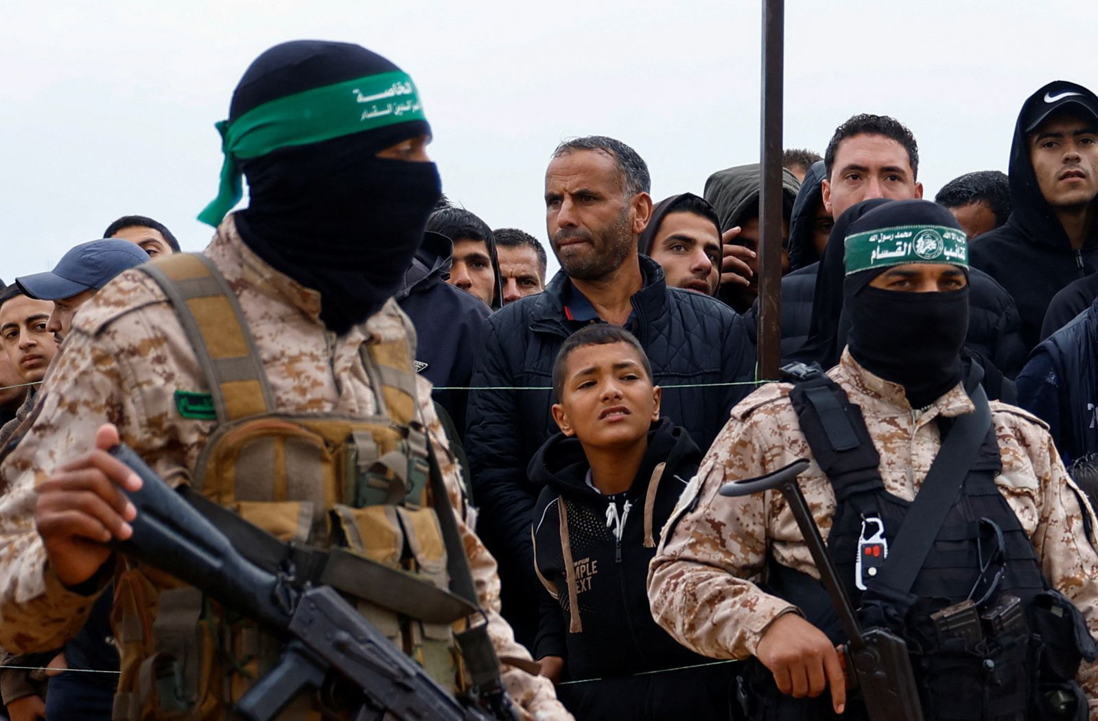 Palestinians gather as Hamas militants stand guard on the day Hamas hands over deceased hostages Oded Lifschitz, Shiri Bibas and her two children Kfir and Ariel Bibas, seized during the deadly October 7, 2023 attack, to the Red Cross, as part of a ceasefire and hostages-prisoners swap deal between Hamas and Israel, in Khan Younis in the southern Gaza Strip February 20, 2025. REUTERS/Hatem Khaled