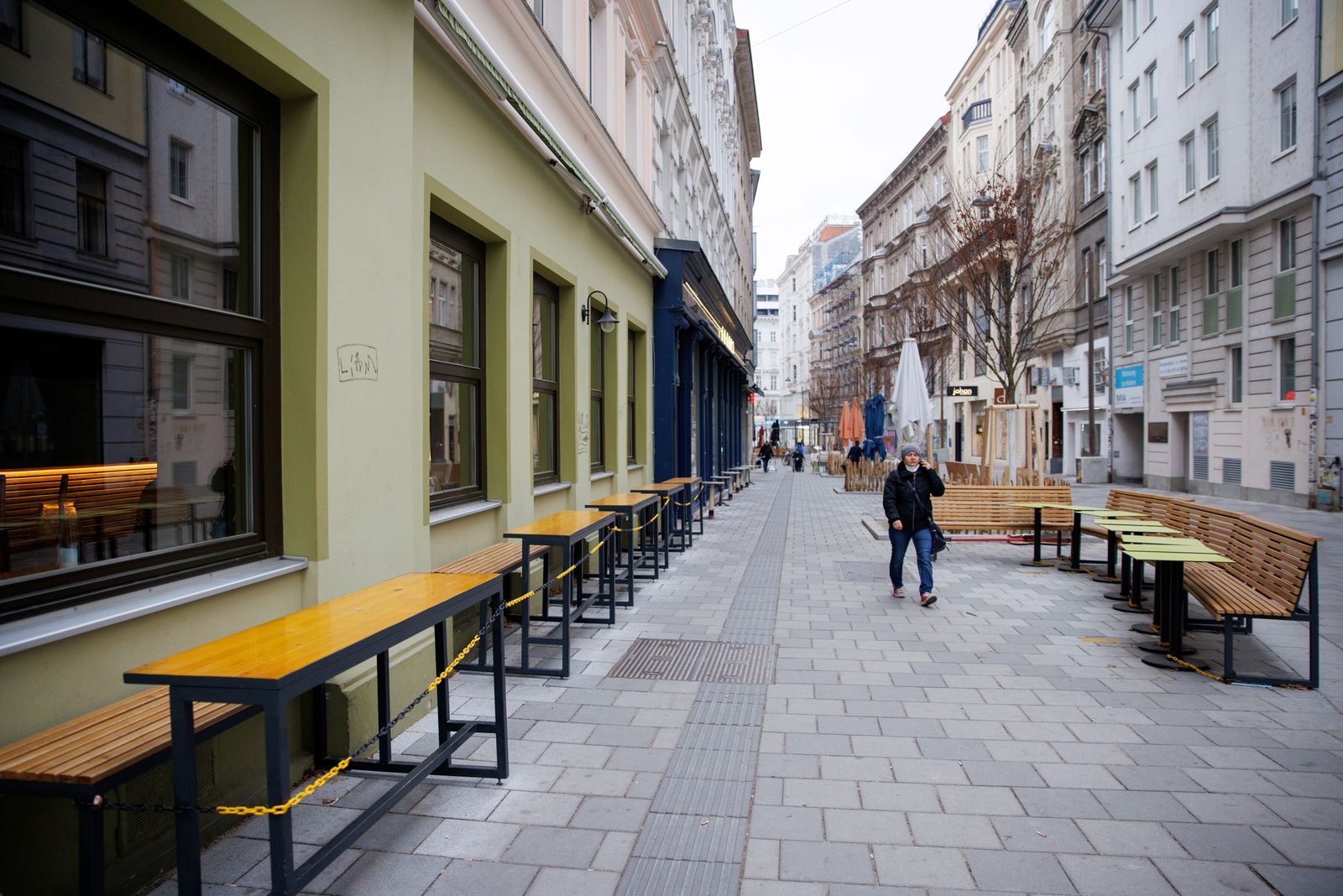 شخص يسير قرب طاولات في مطعم مغلق حيث فرضت الحكومة النمساوية الإغلاق الرابع بسبب كورونا في فيينا، النمسا - 22 نوفمبر 2021 - REUTERS
