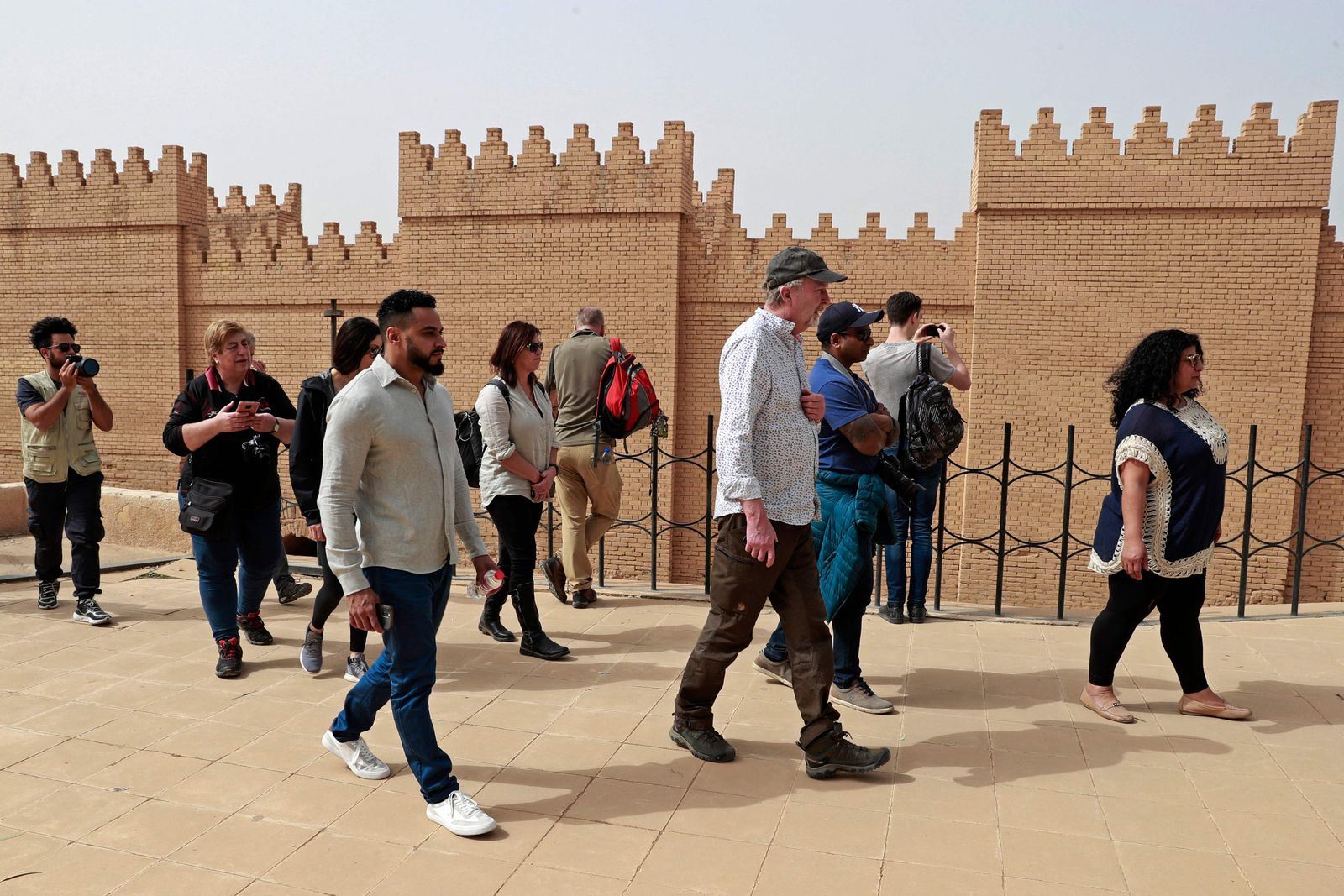 Foreign tourists visit the ancient city of Babylon, some 100 km south of the Iraqi capital Baghdad, on March 7, 2022. - Between the 2003 US invasion, the bloody sectarian conflict that followed, then the rise to power of the Islamic State (IS) group, Iraq for years made the headlines above all for news of conflict and violence. Today, several Western countries still formally advise against travelling to Iraq, but Baghdad seeks to revive its tourism sector, taking up many challenges. (Photo by Ahmad AL-RUBAYE / AFP) - AFP