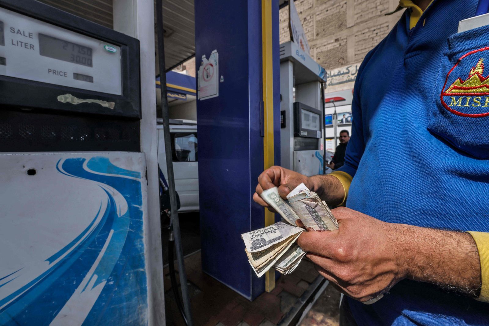 A worker counts money at a petrol station in Cairo on March 2, 2023 as Egypt�s government announced a new increase in fuel prices. (Photo by Khaled DESOUKI / AFP) - AFP
