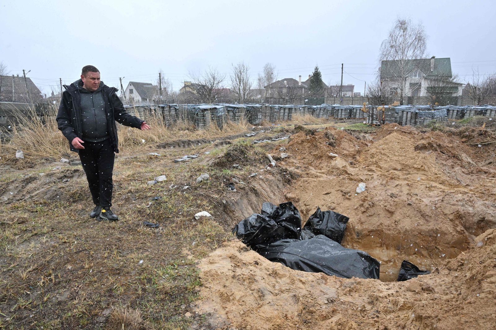 A man gestures at a mass grave in the town of Bucha, northwest of the Ukrainian capital Kyiv on April 3, 2022. - Ukraine and Western nations accused Russian troops of war crimes after the discovery of mass graves and 