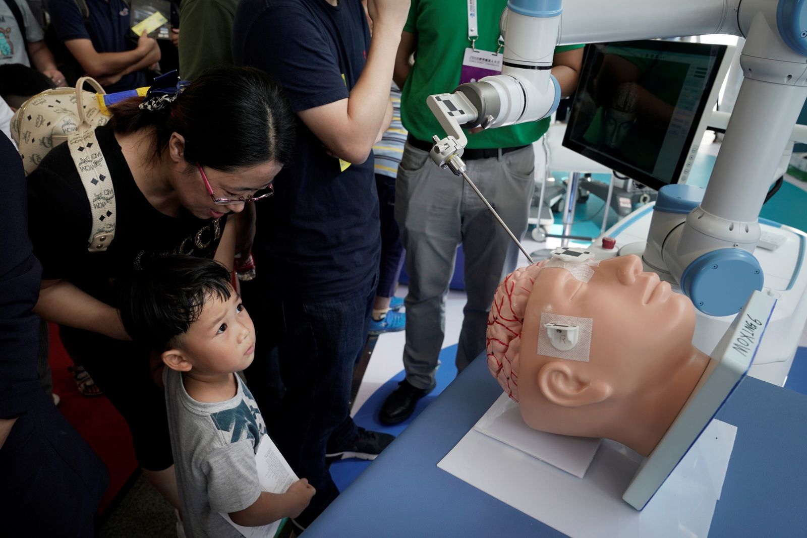 People visit a surgery robot at Tinavi's booth at the WRC in Beijing - REUTERS