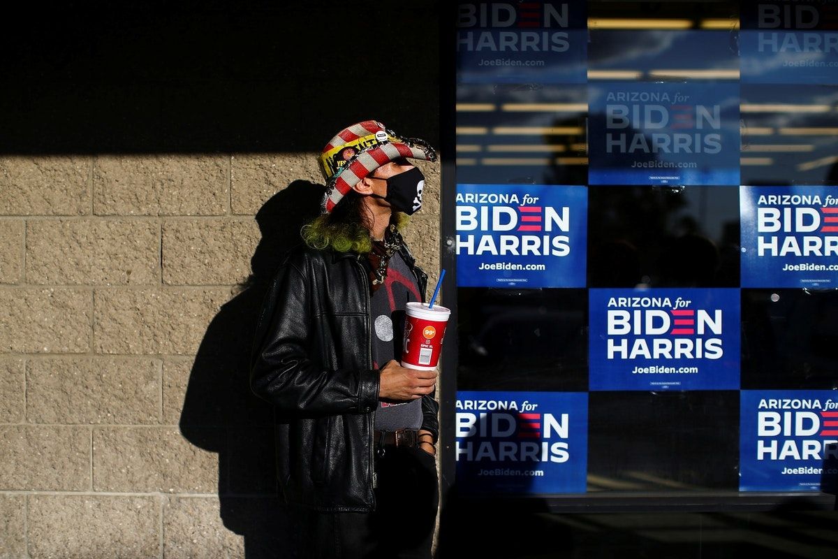 امرأة تقف أمام لافتات مؤيّدة للمرشح الديمقراطي جو بايدن في ولاية أريزونا - REUTERS