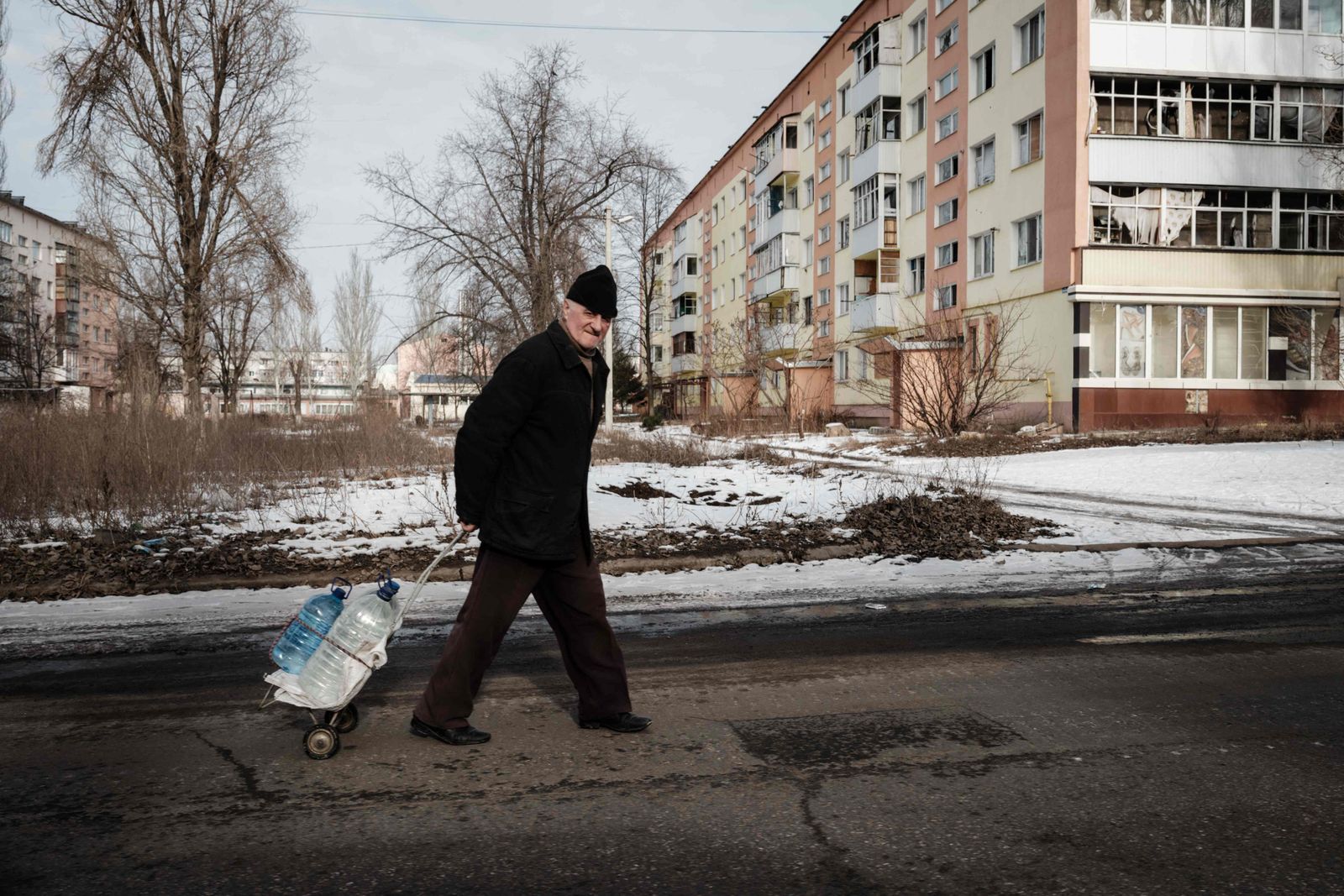 A man carries water containers along the street in Bakhmut on February 9, 2023, amid the Russian invasion of Ukraine. (Photo by YASUYOSHI CHIBA / AFP) - AFP