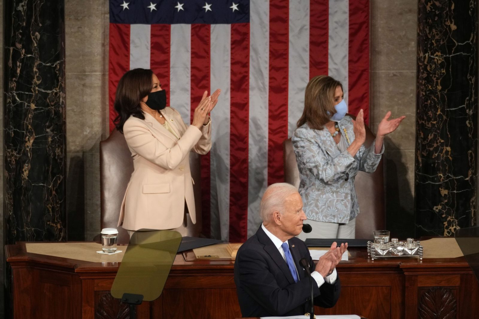 الرئيس الأميركي جو بايدن ونائبته كامالا هاريس (يسار) ورئيسة مجلس النواب نانسي بيلوسي يصفقون خلال إلقاء الرئيس خطابه أمام الكونغرس - 28 أبريل 2021 - Bloomberg